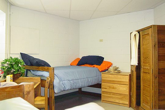 Keystone College dorm room with bed and wooden hutch and armoire