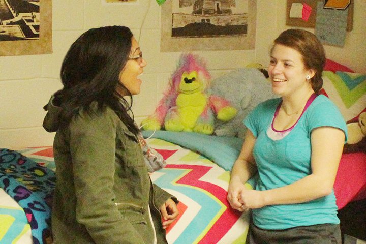 a resident assistant speaks to another student in a dorm room