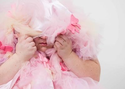 a woman hiding under pink toule