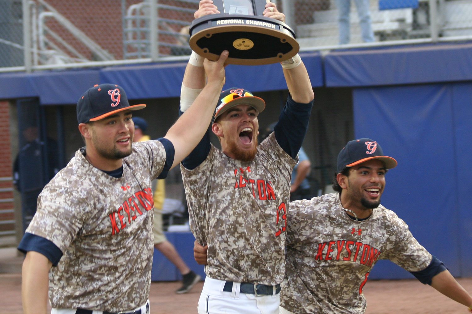 Three baseball players hoist a trophy