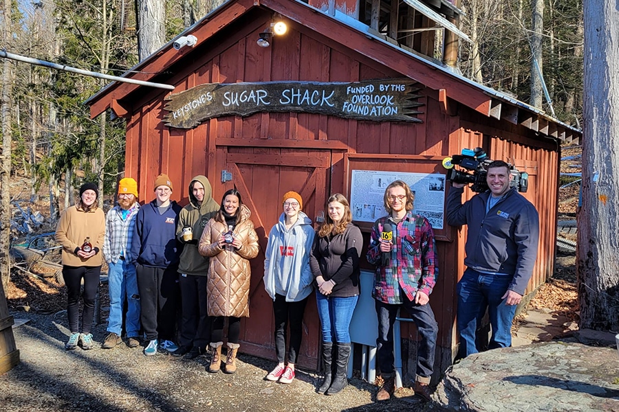 WNEP's Ally Gallo. Kelley Stewart, KCEEI Director, and biology students in front of the Sugar Shack