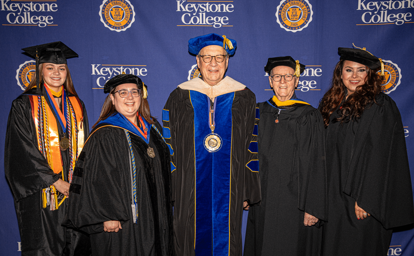 Keystone College President John F. Pullo, Sr. ’69, center, gathers with participants prior to the College’s 155th Commencement on Saturday, May 16, on campus in La Plume. Joining Pullo are: Kirby K. Hickey ’65, Board of Trustees Chair; Maggie Calpin ’09, Commencement Speaker; Amber Mascia, 2026 Outstanding Graduate; and Vicki A Stanavitch, Ph.D. ’92, Provost and Vice President of Academic and Student Affairs. (Photo courtesy of Timothy R. Dougherty Photography)
